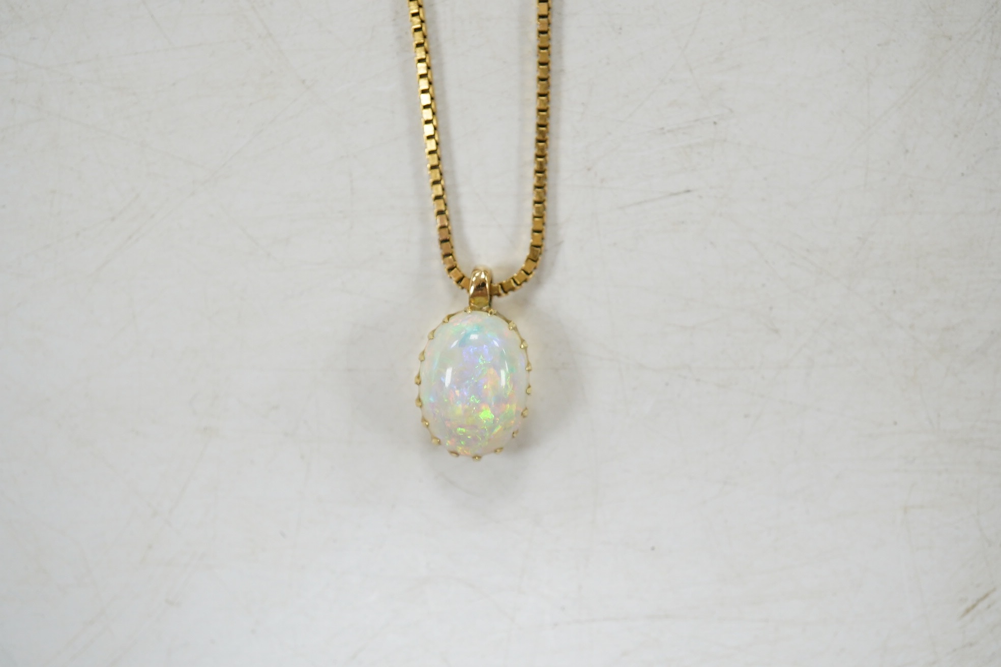 A modern 9kt and single stone oval cabochon white opal set pendant necklace, overall 36cm, gross weight 4.9 grams. Condition - fair to good